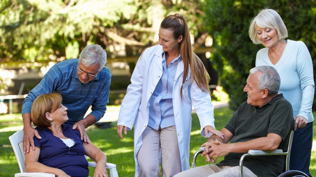 Menschen im Garten mit Pflegekraft im Gespräch
